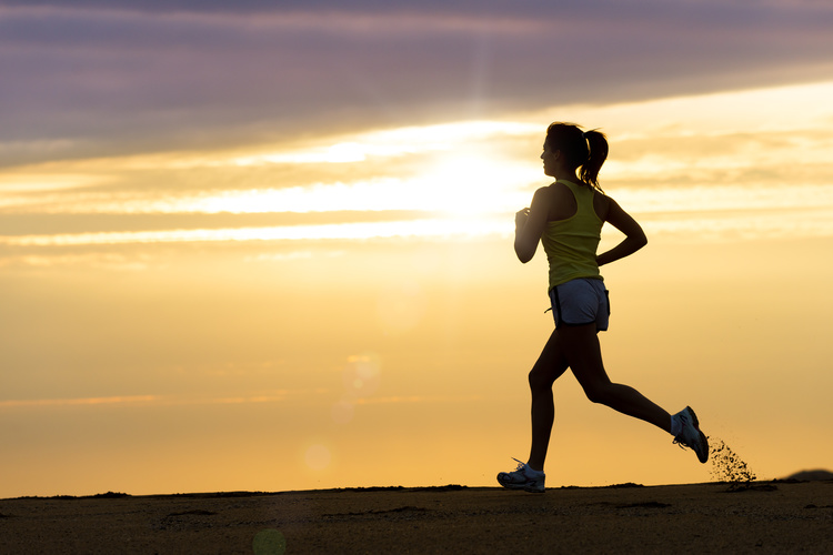 Woman running alone on beautiful sunset in the beach. Summer sport and freedom concept. Athlete training on dusk.